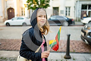 Cute young girl holding tricolor Lithuanian flag on Lithuanian Statehood Day