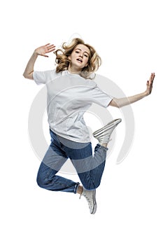 A cute young girl is jumping. A teenager in a white T-shirt and blue jeans. Activity and positive. Isolated on white background.