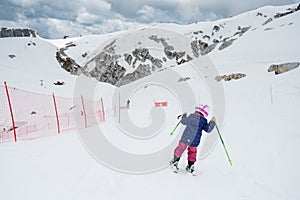 Cute young girl learning to ski at winter resort on a sunny day.