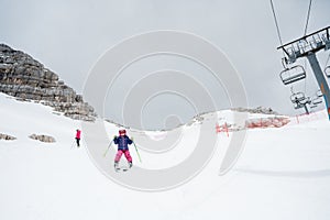 Cute young girl learning to ski at winter resort on a sunny day.