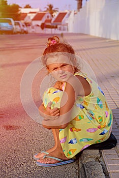 Cute young girl looking sad, alone, scared, abuse, homeless is sitting on the ground. Evening time. Nice sunlight. 2