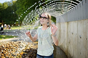 Cute young girl playing in a fountain in Moletai town, one of the oldest settlements in Lithuania and a popular resort for the