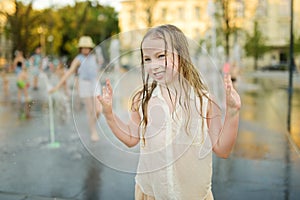 Cute young girl playing in fountains on newly renovated Lukiskes Square in Vilnius, Lithuania. Child having fun with water on