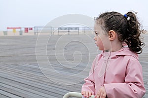 cute young girl playing with her toy stroller on the boarwalk