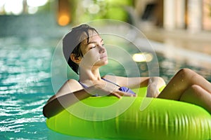 Cute young girl playing with inflatable ring in indoor pool. Child learning to swim. Kid having fun with water toys. Family fun in