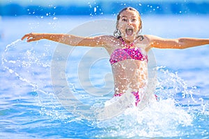 Cute young girl playing in the sea. Happy pre-teen girl enjoys summer water and holidays in holiday destinations