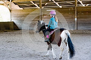 cute young girl riding her pony in a horse farm
