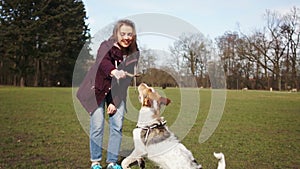 Cute young girl on a walk with a beautiful dog in the park. Mistress plays stick with her dog in the park while walking