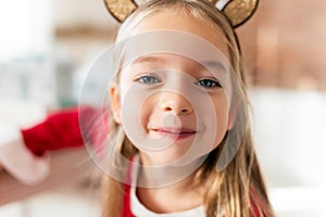 Cute young girl wearing costume reindeer antlers, smiling and looking at camera. Happy kid at christmas.