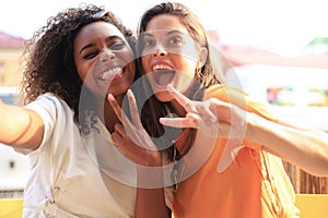 Cute young girls friends having fun together, taking a selfie while sitting at cafe