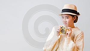 Cute young grumpy Asian tourist woman holding camera in her hand with disappointing expression on her face isolated in grey