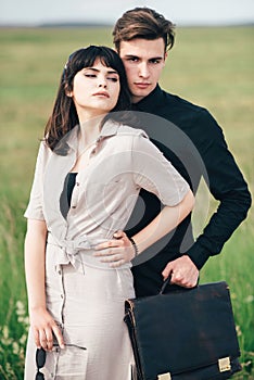 A cute young guy stands next to a pretty girl in whose hands a business bag