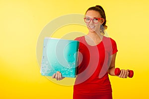 cute young happy caucasian woman in red t shirt over vibrant yellow background gesture power of knowledge hodling a dumbbell and