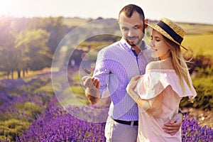 Cute young happy couple in love in a field of lavender flowers. Enjoy a moment of happiness and love in a lavender field.