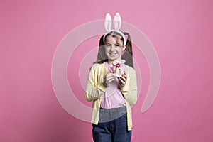 Cute young kid posing with a pink stuffed rabbit toy in studio