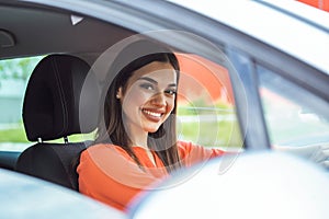 Cute young lady happy driving car. Image of beautiful young woman driving a car and smiling. Portrait of happy female driver