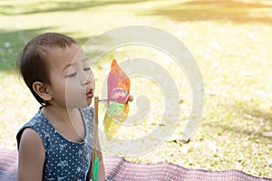 Cute young little girl with a colourful toy windmill peering out from underneath with a charming smile