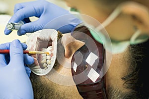 Cute young man smiling looking camera. Female dentist checking patient teeth with mirror in modern dental clinic