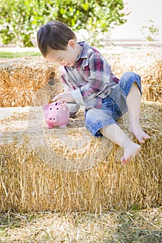 Cute Young Mixed Race Boy Putting Coins Into Piggy Bank