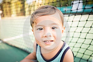 cute young mixed race boy smiling in the sun on the court