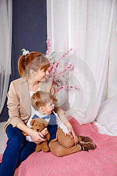 Cute young mother hugs her little son in bed. Mommy and son rest.