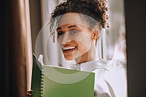 Cute young mulatta holding a notebook and smiling