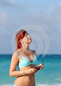 Cute young redhead woman enjoy sun at the ocean shore