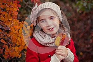 Cute young russian girl stylish dressed in warm red handmade jacket blue jeans boots and hooked headband scarf posing in autumn co photo