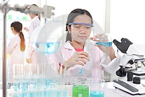 Cute young scientist schoolgirl in lab coat do science experiments. Student girl use equipment to study chemistry in school