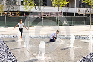 Cute young sisters playing in fountains. Children having fun with water on sunny summer day. Active leisure for kids.