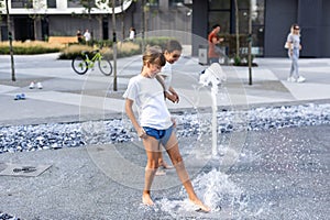 Cute young sisters playing in fountains. Children having fun with water on sunny summer day. Active leisure for kids.
