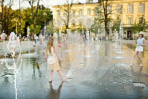 Cute young sisters playing in fountains on newly renovated Lukiskes Square in Vilnius, Lithuania. Children having fun with water