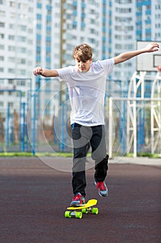 Cute young sport boy skating on yellow skateboard and has a good time on his free time on weekend, holidays. healthy sport