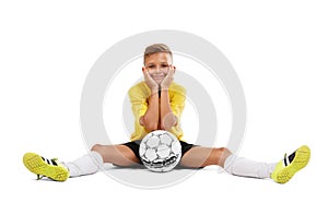 A cute young sportsman in a yellow T-shirt and black shorts sitting on a floor isolated on a white background.