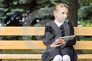 Cute young student girl with tablet sitting in the park