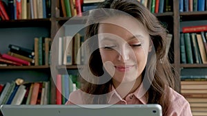 Cute young student using a tablet computer in a library