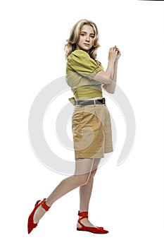 A cute young teen girl in beige shorts and a green blouse is standing. Isolated on white background. Vertical