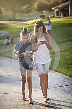Cute young teen girls texting on their mobile cell phone outdoors