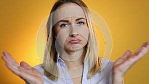 A cute young white woman makes a sad face on a yellow background