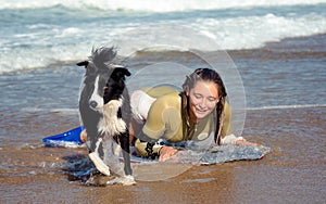 Cute young woman bodyboarding in swimsuit with her dogs