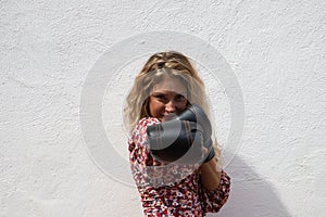 Cute young woman with boxing gloves and white top makes different gestures and expressions on white background. Woman is having