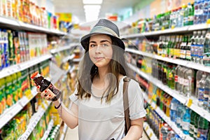 Cute young woman chooses a bottle of juice in the supermarket. Tint