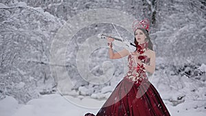 Cute young woman in fairy tale image in grey royal dress plays white violin on snow