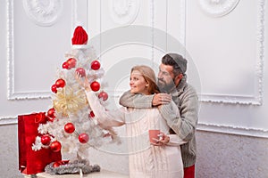 Cute young woman and handsome man celebrate Happy new year. Happy couple over christmas tree lights background.