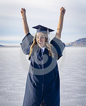 Cute Young woman in her graduation cap and gown showing excitement after graduating