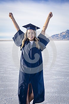 Cute Young woman in her graduation cap and gown showing excitement after graduating