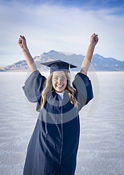 Cute Young woman in her graduation cap and gown showing excitement after graduating