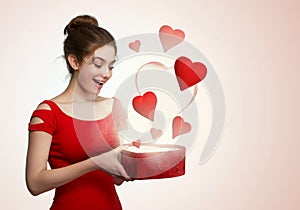 Cute young woman holding a box with red heart flying out