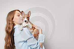 Cute young woman hugging and kissing her puppy basenji dog. Love between dog and owner. Isolated on white background