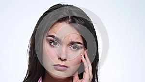 A cute young woman makes a sad face on a white background